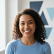 A smiling woman in her late 20s wearing a light blue top, with a soft white and blue background, looking genuinely happy and 